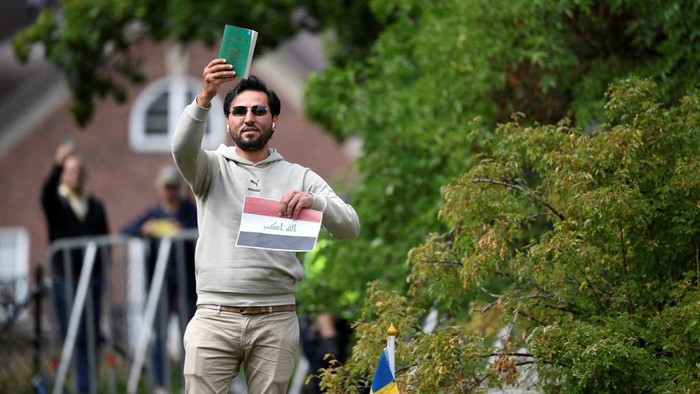 Protestor Salwan Momika holds up the Muslim holy book and a sheet of paper showing the flag of Iraq during a protest outside the Iraqi Embassy in Stockholm, Sweden, on July 20, 2023. Iraq warned Sweden on July 20, 2023 that it would cut diplomatic relations if a Koran-burning protest is allowed to go ahead in Stockholm, after protesters stormed and torched the Swedish embassy in Baghdad overnight. (Photo by Oscar Olsson / TT News Agency / AFP) / Sweden OUT