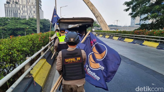 Satpol PP menertibkan bendara Partai NasDem yang dipasang di Flyover Pancoran, Jakarta. Penertiban ini dilakukan karena izin pemasangan bendara telah berakhir.