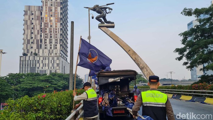 Satpol PP menertibkan bendara Partai NasDem yang dipasang di Flyover Pancoran, Jakarta. Penertiban ini dilakukan karena izin pemasangan bendara telah berakhir.