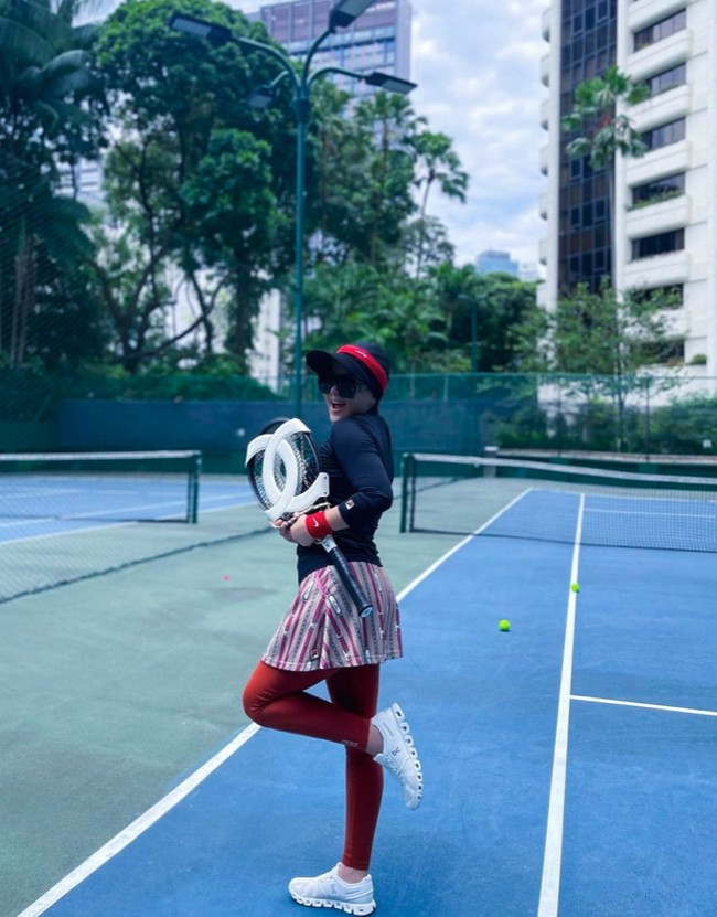 Ini merupakan salah satu inspirasi gaya hijab Syahrini saat main tenis. Tetap sporty menggunakan baju olahraga maroon-hitam dan raket Chanel. Foto: Instagram @princessyahrini