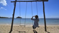 Wisatawan duduk di bangku ayunan di pinggiran Pantai Elak-Elak, Sekotong, Lombok Barat, NTB, Sabtu (22/7/2023). 