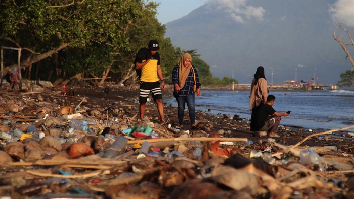 Pengunjung menikmati suasana pantai di dekat sampah yang berserakan di Pantai Kastela, Kota Ternate, Maluku Utara, Minggu (23/7/2023). Sampah kiriman yang terdampar dan mencemari kawasan wisata pantai tersebut karena terbawa gelombang laut dan angin kencang yang terjadi beberapa hari terakhir.ANTARA FOTO/Andri Saputra/nz.