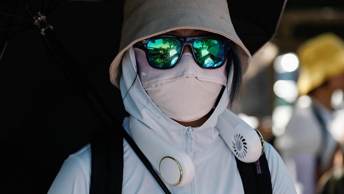 A person wearing sun protection face mask amid a heatwave walks on a street in Beijing, China July 1, 2023. REUTERS/Tingshu Wang
