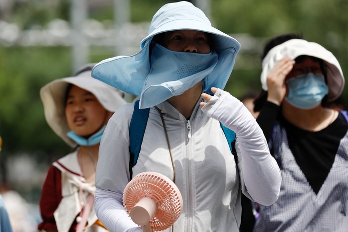 A person wearing sun protection face mask amid a heatwave walks on a street in Beijing, China July 1, 2023. REUTERS/Tingshu Wang