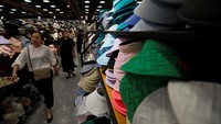 Para pembeli berjalan melewati tutup kepala pelindung matahari yang dipajang di sebuah toko di pusat perbelanjaan di Beijing, China. (REUTERS/Florence Lo)