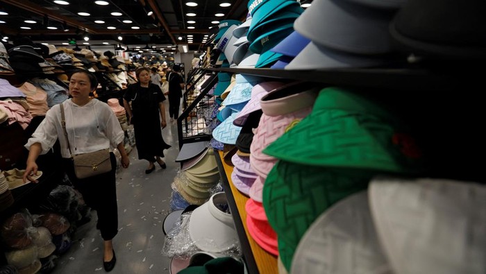 Shoppers walk past sun protection headgear displayed at a store in a shopping mall, amid a yellow alert for heatwave in Beijing, China July 19, 2023. REUTERS/Florence Lo)