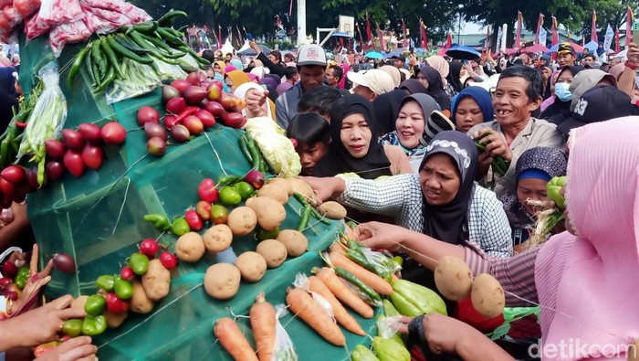 Rebutan gunungan hasil bumi saat pisowonan agung di Alun-alun Wonosobo, Senin (24/7/2023).
