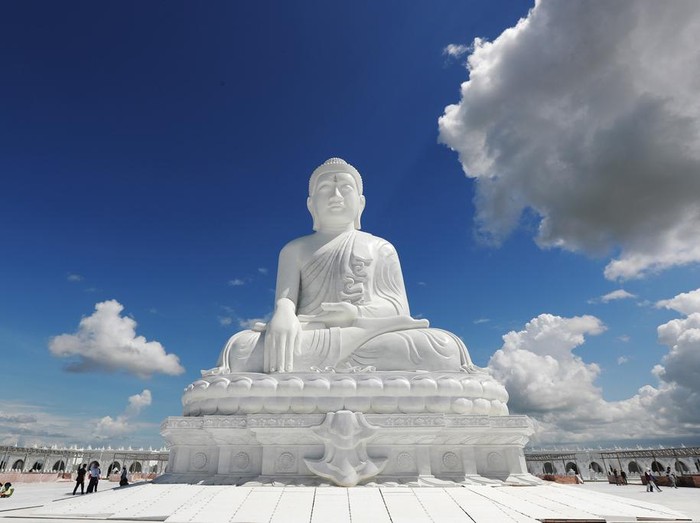 Laborers work while visitors stand below the sitting Maravijaya Buddha marble statue, Friday, July 21, 2023, in Naypyitaw, Myanmar. The Maravijaya Buddha statue is said to be the world’s highest sitting marble Buddha image according to local media. (AP Photo/Aung Shine Oo)