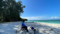 Seorang wisatawan lokal duduk pantai Pulau Meoskun sambil menikmati pemandangan Raja Ampat