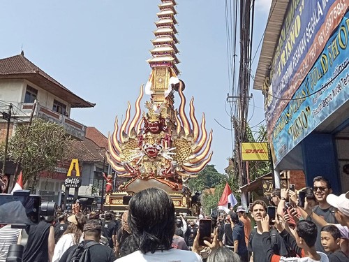 Wisatawan menyaksikan prosesi iring-iringan pelebon Mantan Bupati Gianyar Cok Budi Suryawan.