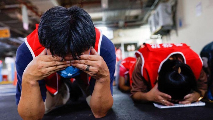 Shop and restaurant owners participate in a military drill at a basement parking lot, as they are instructed to cover their eyes and ears while keeping their mouths open, in order to minimize the impact of blast waves from missiles, in Taipei, Taiwan July 24, 2023. REUTERS/Ann Wang