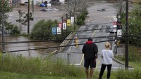 Orang-orang berdiri di atas bukit mengamati mobil yang terbengkalai di tempat parkir mal setelah hujan lebat di Halifax, Nova Scotia, Kanada, Sabtu (22/7/2023). Empat orang hilang setelah badai petir hebat mengguyur wilayah tersebut. 