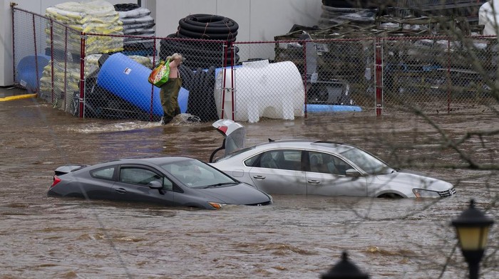 Penampakan Banjir Bandang yang Melanda Kanada A man wearing chest waders walks past cars abandoned in floodwaters in a mall parking lot following a major rain event in Halifax, Nova Scotia, Canada, on Saturday, July 22, 2023. (Darren Calabrese/The Canadian Press via AP)