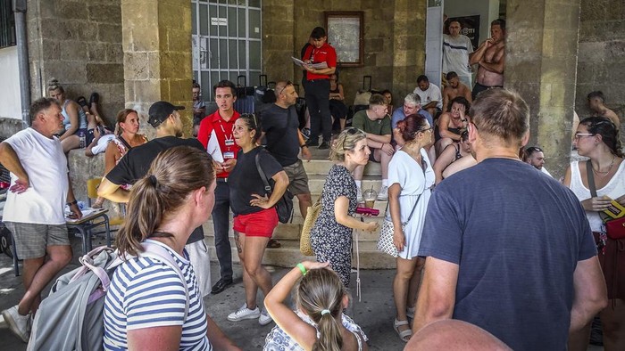 Evacuees gather outside a building following their evacuation during a forest fire on the island of Rhodes, Greece, Sunday, July 23, 2023. Some 19,000 people have been evacuated from the Greek island of Rhodes as wildfires continued burning for a sixth day on three fronts, Greek authorities said on Sunday. (Argyris Mantikos/Eurokinissi via AP)