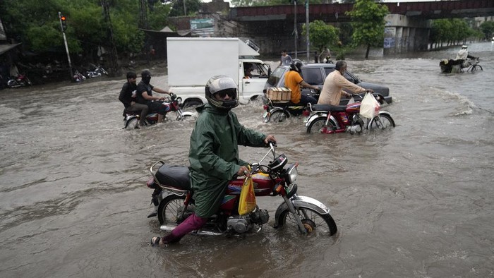 Puluhan Orang Tewas Saat Banjir Bandang Melanda Afghanistan dan Pakistan Motorcyclists drive through a flooded road caused by heavy monsoon rainfall in Lahore, Pakistan, Saturday, July 22, 2023. (AP Photo/K.M. Chaudary)
