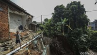 Warga beraktivitas di rumah terdampak longsor di Cipayung, Depok, Selasa (25/7/2023). Longsor yang terjadi sejak 3 minggu lalu mengakibatkan kerusakan pada tiga rumah.  