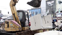 Alat berat mengangkut box culvert ke galian saluran air.  