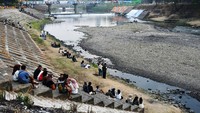 Sejumlah muda-mudi sedang bersantai di turap Sungai Madiun, Jawa Timur, Selasa (25/7/2023). Selain itu ada juga yang duduk-duduk di dasar sungai yang mengering.   