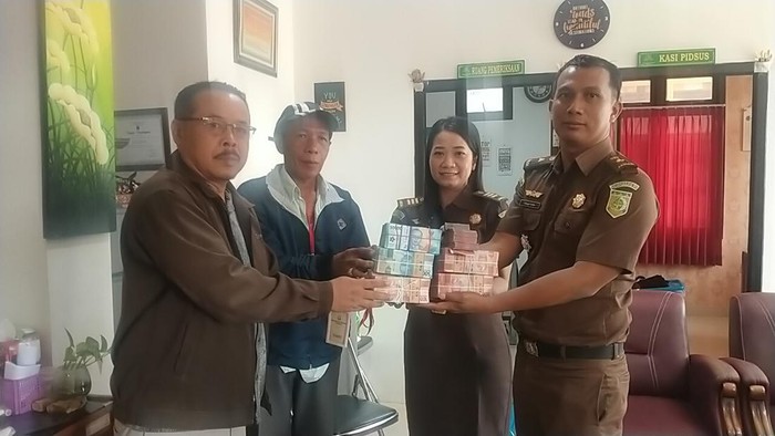 Kasipidsus Kejari Tabanan I Nengah Ardika (kanan) menyerahkan uang pengganti yang diserahkan terpidana korupsi LPD Sunantaya, I Gede Wayan Sutarja, kepada pengurus LPD dan Bendesa Adat Sunantaya yang baru.