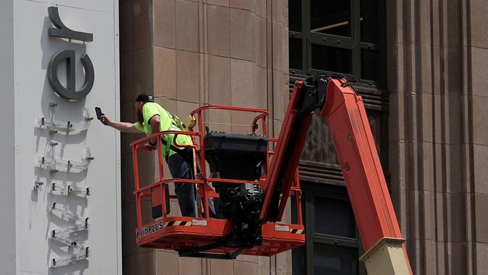 A worker uses a smartphone while dismantling a Twitters sign at Twitters corporate headquarters building as Elon Musk renamed Twitter as X and unveiled a new logo, in downtown San Francisco, California, U.S., July 24, 2023. REUTERS/Carlos Barria TPX IMAGES OF THE DAY