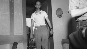 Sersan Herbert Lehr mengirimkan inti plutonium untuk perangkat dalam tas jinjing yang terhubung ke ruang perakitan di rumah pertanian McDonald Ranch. Foto: Atomicarchive