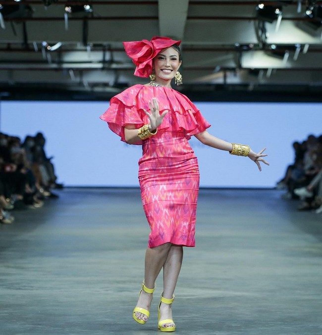 Jadi muse desainer Renzi Lazuardi, Ayu Dewi tampil cerah dengan gaun pink motif tenun ikat. Penampilannya makin girlie berkat aksen ruffle dan topi bentuk bunga. Foto: Dok. JF3