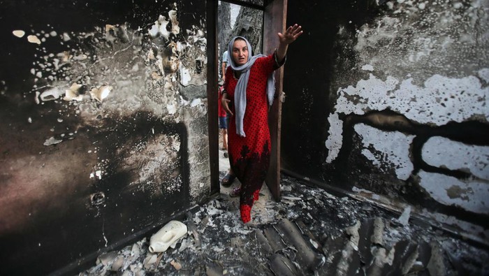 Souhila Belkati carries her child inside her burnt house, following a wildfire in Bejaia, Algeria July 25, 2023. REUTERS/Ramzi Boudina     TPX IMAGES OF THE DAY