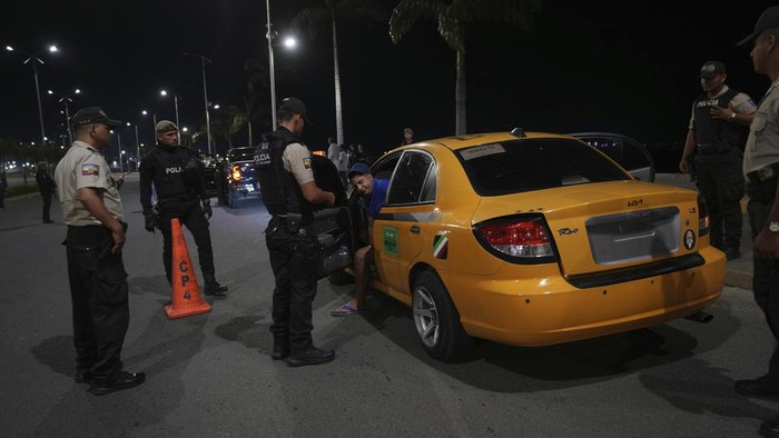 Police stand on a median during the start of a curfew decreed by Ecuador´s President Guillermo Lasso to try to reduce the ongoing wave of violence in Manta, Ecuador, Monday, July 24, 2023. (AP Photo/Dolores Ochoa)