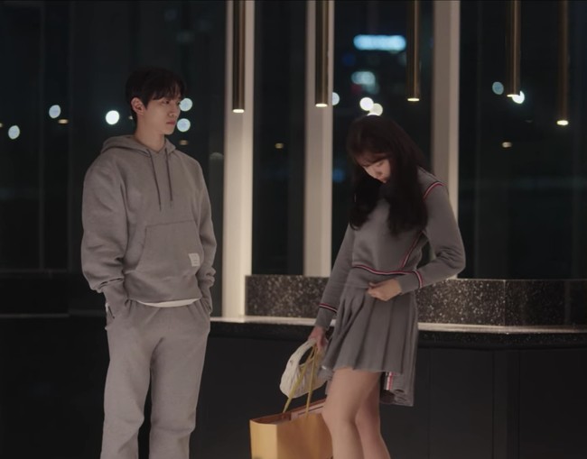 Tak kalah gemas. Yoona memakai baju couple dengan Lee Junho dari koleksi Thom Browne, jersey sweater abu-abu seharga $643 (Rp 9 jutaan) dan mini skirt $790 (Rp 11 jutaan) dengan koleksi sling bag dan sneakers Miu Miu. Foto: dok. Netflix