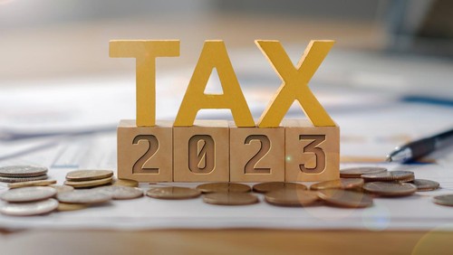 The word TAX is on a wooden block, 2023 is below. Income tax payment concept.  Return of personal income tax payable to the government  Calculation of tax returns in the years 2022 to 2023, etc.