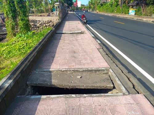 Kondisi trotoar di kawasan lovina yang berlubang, Selasa (25/7/2023). (Made Wijaya Kusuma)