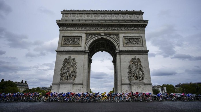 Menikmati Indahnya Lanskap Kota Paris The pack with Denmark's Jonas Vingegaard, wearing the overall leader's yellow jersey, center, passes Arc de Triomphe during the twenty-first stage of the Tour de France cycling race over 115 kilometers (71.5 miles) with start in Saint-Quentin-en-Yvelines and finish on the Champs-Elysees avenue in Paris, France, Sunday, July 23, 2023. (AP Photo/Daniel Cole)