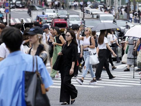 Orang-orang berjalan melintasi penyeberangan pejalan kaki di distrik Shibuya dalam cuaca panas dan lembab Kamis, 13 Juli 2023, di Tokyo. (AP Photo/Eugene Hoshiko)