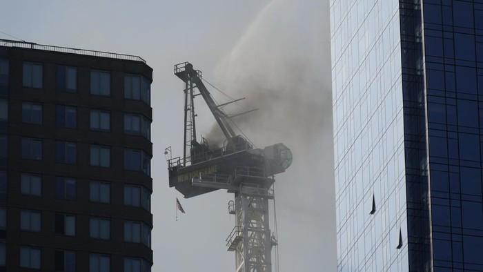 Crane Terbakar dan Ambruk di Jalanan New York, 12 Orang Terluka Smoke rises from a construction crane that caught fire in Manhattan, Wednesday, July 26, 2023, in New York. The crane lost its long arm, which smashed against a nearby building, dangled and then plummeted to the street as people ran for their lives on the sidewalk below. Some people suffered minor injuries, but no one died, according to Mayor Eric Adams .(AP Photo/Seth Wenig)