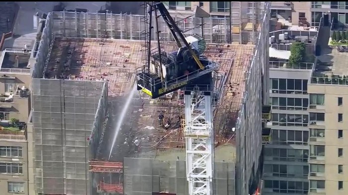 Crane Terbakar dan Ambruk di Jalanan New York, 12 Orang Terluka Emergency responders are on the scene after a large construction crane caught fire in Manhattan on Wednesday, July 26, 2023 in New York. The crane caught fire and its arm hit a building as it crashed to the street below. (WABC via AP)