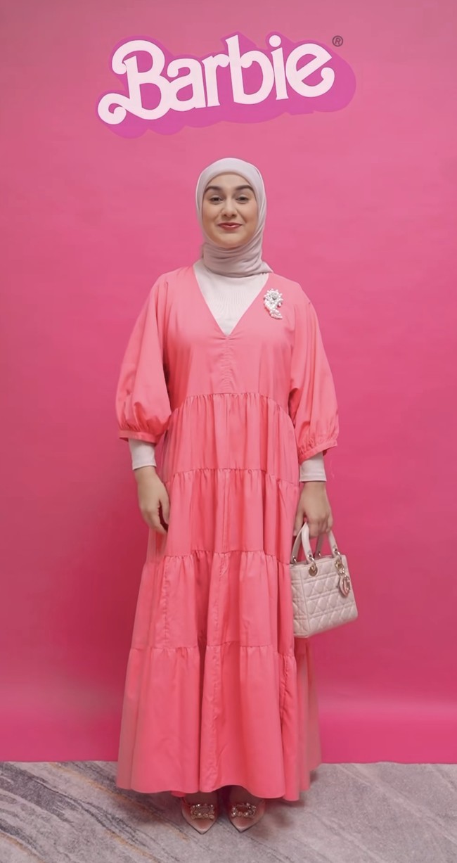 Irish Bella mencoba tampil a la Barbie dengan padu padan gaya hijab simple dan dress panjang warna merah muda. Dress berpotongan kerah V-neck itu dilengkapi dengan manset putih yang membantu menutupi area dada serta lengan. Foto: Dok. Instagram Irish Bella