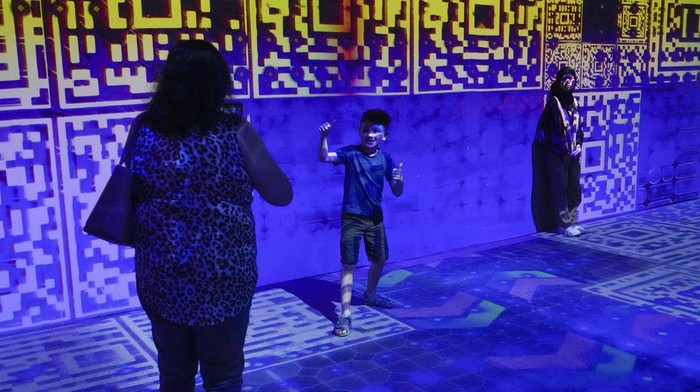 A child poses for a picture during a light projection art exhibition titled 