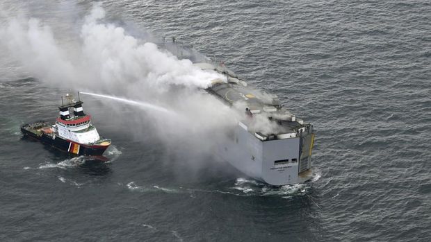Sebuah perahu menyemprot asap dari kebakaran yang terjadi di sebuah kapal barang di Laut Utara, sekitar 27 kilometer (17 mil) utara pulau Belanda Ameland, Rabu, 26 Juli 2023. Kebakaran di kapal barang Fremantle Highway, yang membawa hampir 3.000 mobil, terbakar di luar kendali pada hari Rabu di Laut Utara, dan penjaga pantai Belanda mengatakan sedang berupaya menyelamatkan kapal agar tidak tenggelam di dekat habitat penting bagi burung migran. (Kustwacht Nederland/Coast Guard Netherlands via AP)
