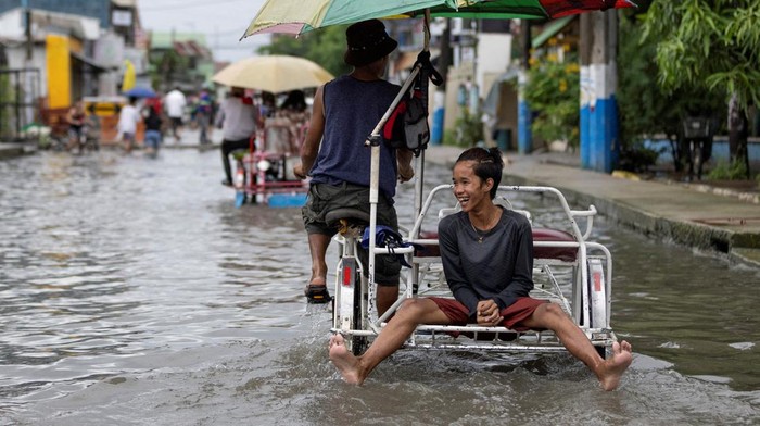 Filipina Banjir Bandang Diterjang Topan Doksuri Commuters wade through a flooded street in the aftermath of typhoon Doksuri, in Valenzuela, Metro Manila, Philippines July 27, 2023. REUTERS/Eloisa Lopez