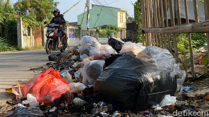 Pengendara motor melintas di Jalan Rancasawo, Kecamatan Buahbatu, Kota Bandung yang dipenuhi tumpukan sampah.
