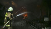 Petugas damkar menembus asap hitam untuk memadamkan api yang terus membesar. 