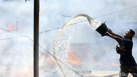 Warga berjibaku menyiramkan berember-ember air untuk membantu memadamkan api. 
