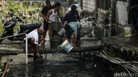 Warga mengoper-oper ember berisi air kemudian disiramkan ke rumah yang terbakar. 