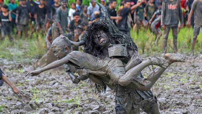 Kebo-keboan, Tradisi Menolak Bala di Banyuwangi Warga yang berdandan seperti kerbau menceburkan penonton ke dalam lumpur sawah pada tradisi Kebo-keboan Alas Malang di Banyuwangi, Jawa Timur, Minggu (30/7/2023). Tradisi yang dilaksanakan setiap tanggal 10 Suro pada penanggalan Jawa itu digelar sebagai penolak bala sekaligus wujud syukur masyarakat setempat atas rezeki dan panen yang telah diperoleh. ANTARA FOTO/Budi Candra Setya/YU