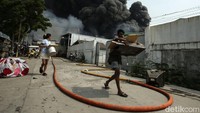 Warga berupaya menyelamatkan barang-barangnya saat api masih berkobar melalap permukiman di Gang Manggis. 