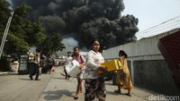 Sejumlah warga mengevakuasi harta bendanya dari kebakaran yang melanda Gang Manggis, Jalan Kapuk Utara II, Kapuk Muara, Jakarta Utara, Minggu (30/7/2023). 
