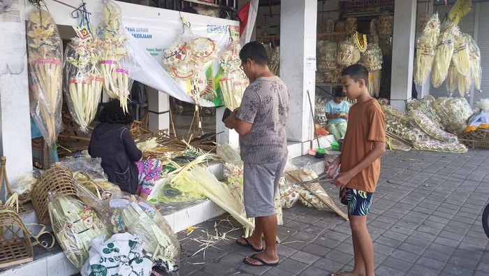 Pedagang hiasan penjor di Jalan Teuku Umar, Karangasem, Bali, saat melayani pembeli pada Minggu (30/7/2023).