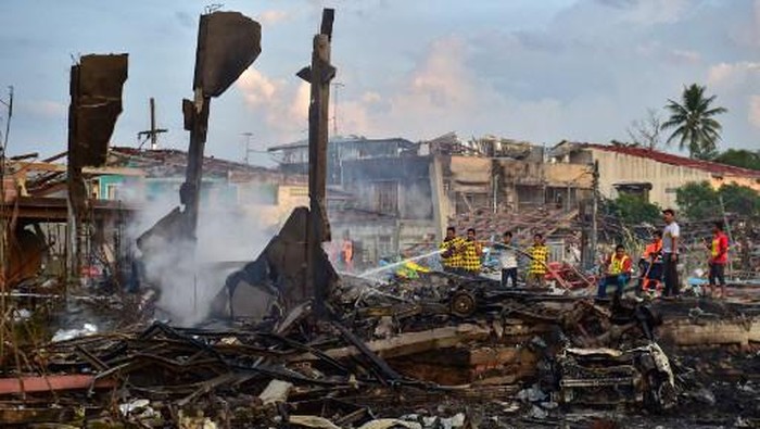 Thai firefighters put out embers around destroyed homes after an explosion ripped through a firework warehouse, killing nine people and injuring more than 100, in Sungai Kolok district in the southern Thai province of Narathiwat on July 29, 2023. (Photo by Madaree TOHLALA / AFP)
