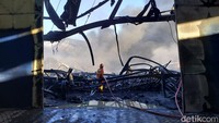 Salah seorang petugas Damkar berdiri di tengah puing-puing sisa kebakaran. Hingga pukul 18.00 WIB, kebakaran belum sepenuhnya padam. Api pokok memang sudah dipadamkan, namun titik-titik api kecil masih terlihat di lokasi. Foto: Jemmi Purwodianto/detikJatim