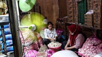 Para pedagang sedang menyiapkan dagangannya di penampungan sementara Pasar Senen. Sementara itu lokasi Blok VI yang direvitalisasi berada persis di belakang bangunan penampungan sementara tersebut.  